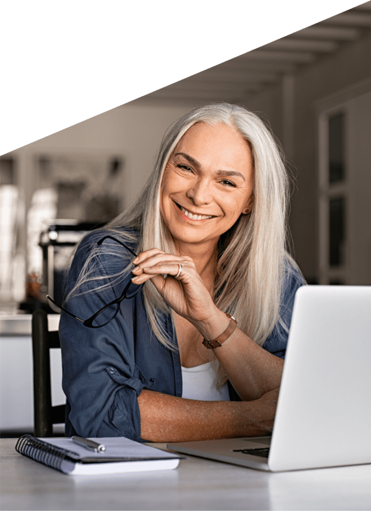 Mature female business manager smiling at home on laptop